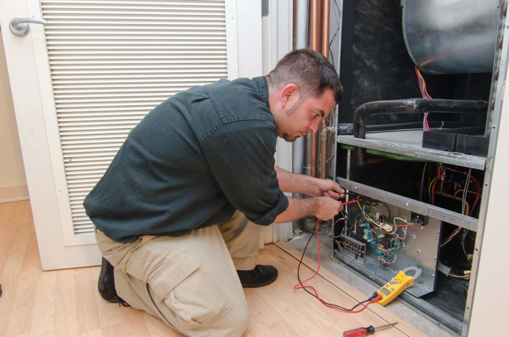 Image of heating tech working on a customer's furnace
