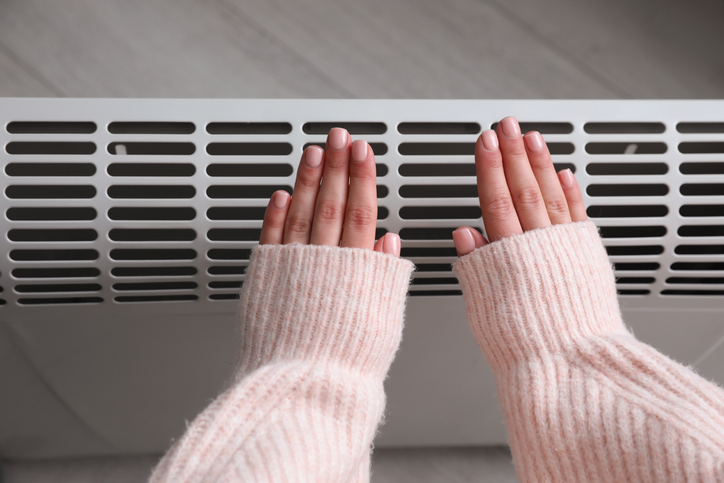 Woman Warming Hands Near Heater